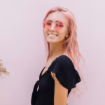 woman-with-long-pink-hair-standing-beside-exotic-palm-trees-studio_197531-21216